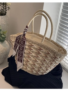 Handwoven straw handbag with beige tones and a red bear scarf on handles