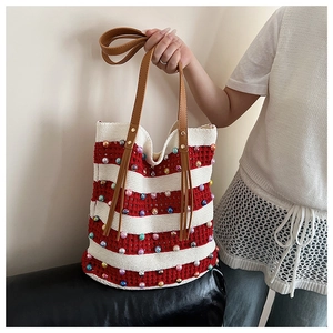 Détail du sac cabas en tricot rayé rouge et blanc avec des perles colorées et anses marron