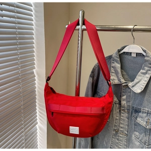 Vue détaillée du sac bandoulière rouge en nylon en forme de croissant avec sangle réglable
