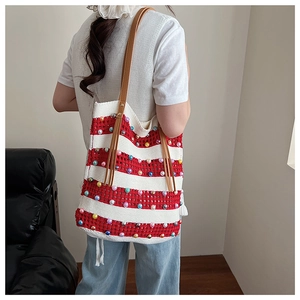 Détail du sac cabas en tricot rayé rouge et blanc avec perles colorées et anses cuir
