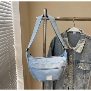 Détail du sac à bandoulière bleu clair en demi-lune avec sangle réglable et poche zippée