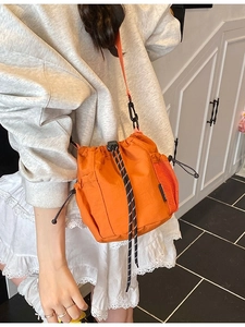 Bright orange canvas drawstring bucket bag with side mesh pocket and striped strap