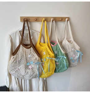 Detail of knitted mesh beach bags with seashell charms and colorful summer ribbon bows