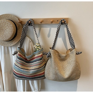 Detail of hand-woven straw tote bags with striped fabric handles for summer beach vacations
