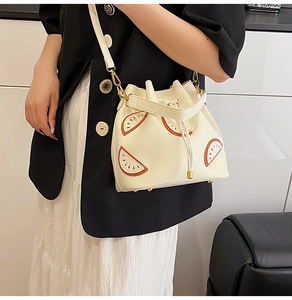 Detail of white drawstring bucket bag with fruit applique and adjustable shoulder strap