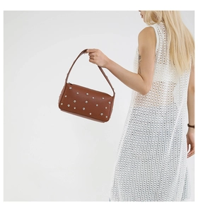 Close-up of brown pebbled leather handbag with silver rivets on white background