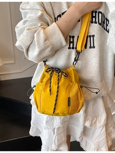 Bright yellow drawstring bucket crossbody bag with mesh pocket and adjustable strap