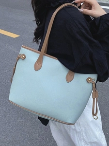 Large blue pebbled leather tote bag with brown straps worn by a model on a clean street