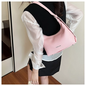 Detail of pink lychee leather dumpling bag with FASHION & BAGS print and metal studs