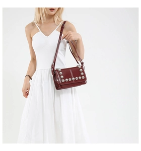 Detail of burgundy patent leather shoulder bag with silver punk studs and adjustable strap