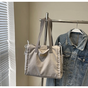 Dettaglio della borsa tote in nylon grigio con coulisse e patch di marca in pelle