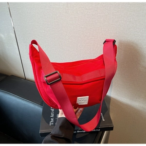 Vue détaillée d'un sac demi-lune en nylon rouge vif avec bandoulière large réglable