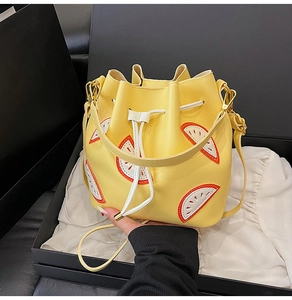 Detail of yellow bucket bag with summer fruit embroidery and golden metal drawstring tips