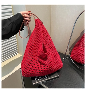 Detail of red hollow woven tote bag with brown leather handles for summer beach use