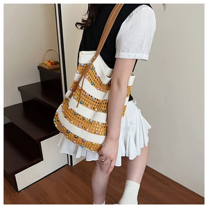 Détail d'un sac cabas tissé à rayures avec accents de perles et bandoulière en cuir