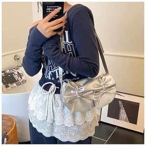 Dettaglio di una borsa a sella argento stile balletto con fiocchi e finitura a specchio