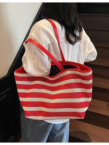 Red and white striped knit tote bag with red leather shoulder straps shown on a model