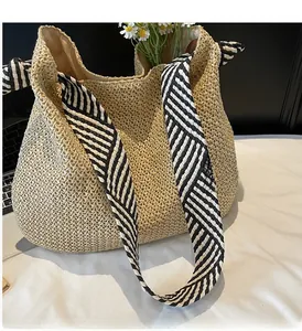 Detail of hand-woven straw tote bag with striped scarf handle and white fabric lining