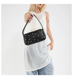 Detail of black lychee grain leather shoulder bag with silver punk rivets on white background