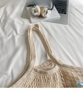 Detail of beige woven tote bag showing wide shoulder strap and soft knit texture