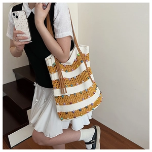 Détail du sac cabas en tricot à rayures avec perles colorées et poignée en cuir marron