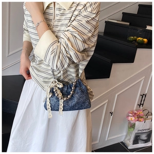 Detail of dark blue glitter bucket bag with silver bead handle and lace bow detail