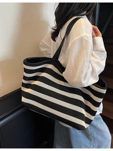 Large black and white striped knit tote bag with leather straps shown on a model
