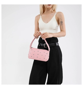 Detail of pink matte leather pillow bag with silver rivets and minimalist handle