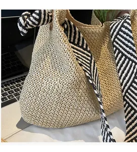 Detailed close-up of beige straw woven tote bag with striped ribbon handles and texture