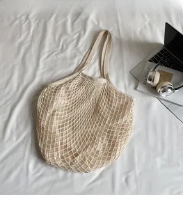 Detail view of cream-white knitted mesh tote bag showing durable woven diamond structure