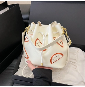 Detail of white bucket bag featuring citrus leather appliques and gold hardware