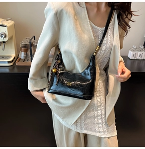 Dettaglio della borsa hobo in pelle cerata nera con finiture dorate e ciondolo a nodo