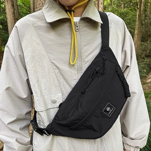 Outdoor shot of a black nylon crossbody bag with textured fabric and zipper details