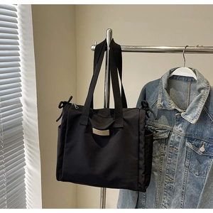 Dettaglio borsa shopper in tela nera con tasche laterali e cerniera a fiocco decorativa