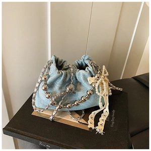 Detail of light blue denim bucket bag with silver chains and white pearl bow accent