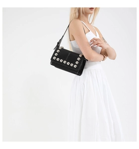 Close-up of a black crossbody bag with silver studs and a punk-style adjustable strap