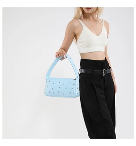 Dettaglio della borsa a spalla in pelle azzurra con borchie argentate e tracolla trendy