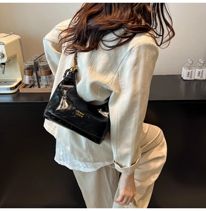 Dettaglio della texture in pelle cerata nera e logo dorato sulla borsa hobo