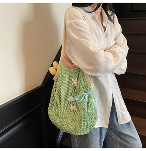 Detail of green woven tote bag with starfish, shells, blue bow and yellow tulips