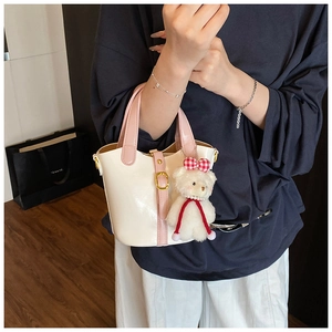 Detail van witte emmer-tas met roze handvatten en een schattige pluche beer-accessoire