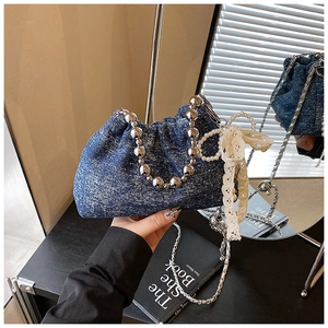 Detail of blue denim bucket bag with silver metal bead handle and pearl lace accents