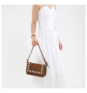 Detail of a brown vintage leather crossbody bag with silver rivet studs and a structured shape
