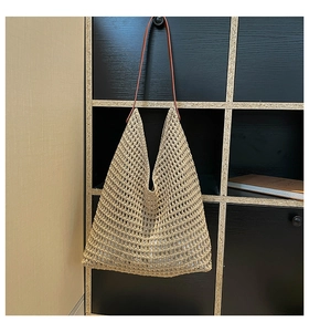 Detail of hollow woven beige tote bag with leather straps on a wall hanger