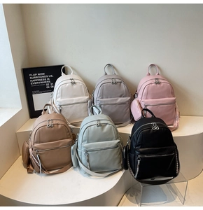 Close-up of minimalist travel backpacks in six colors with mini pouch on a display stand
