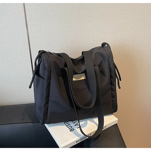 Dettaglio della borsa tote in nylon nero con logo in pelle e pratica tasca laterale