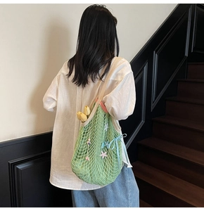 Close-up of woven green tote bag with star charms, blue ribbon and floral decorations