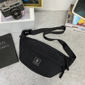 Detail of black nylon fanny pack showing branded label and adjustable strap