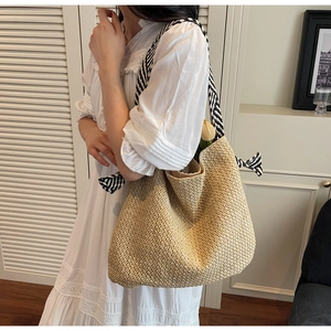 Detail of woven straw tote bag featuring black and white striped bow handle and summer texture