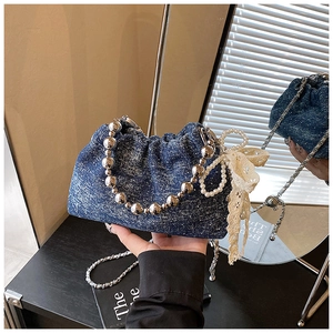 Close-up of blue denim bucket bag featuring silver bead handle and white lace bow detail