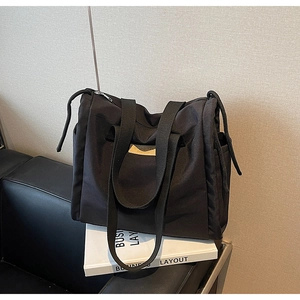 Dettaglio della borsa tote in tela nera con design capiente e toppa in pelle BIDEJO